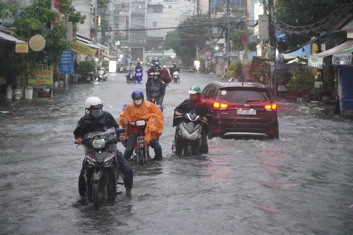 Đường ngập sâu sau mưa lớn, người dân ở TPHCM dắt bộ xe về nhà