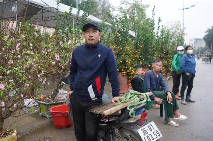 Tiểu thương và người chở thuê đào quất ngồi ngóng người mua tại chợ hoa Tết