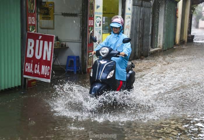Mưa lớn khiến người và xe ở Hà Nội 'bơi' trên phố
