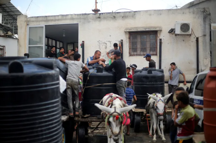 Người đàn ông và chú lừa kéo xe đi phân phát nước ở Dải Gaza